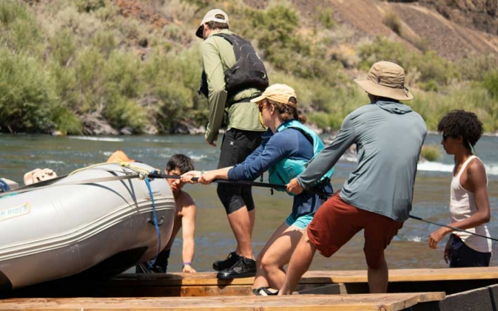 a group of outward bound students haul a raft out of the water onto a trailer